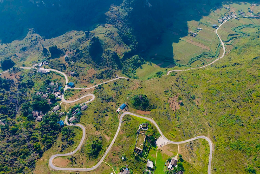 A drone shot capturing the winding road hugging the steep cliffs of the pass
